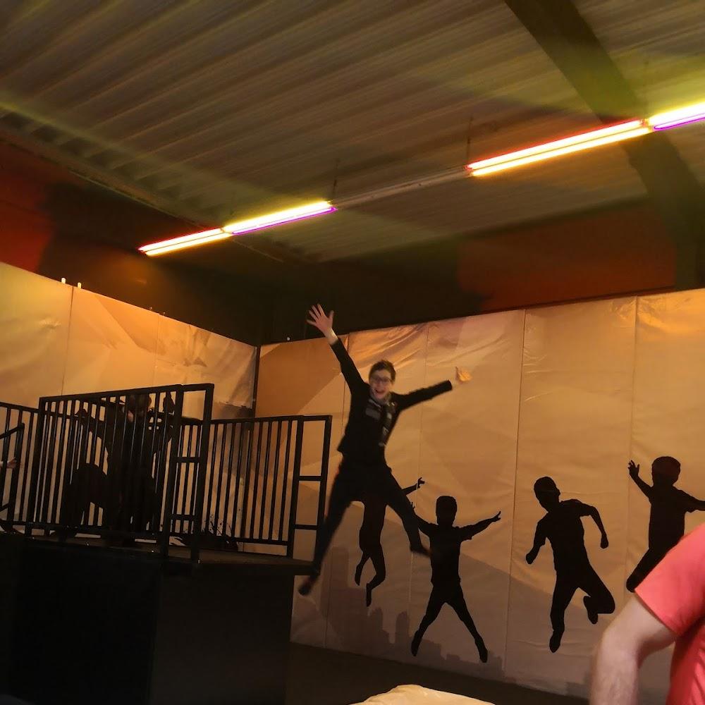 A person jumping in a trampoline park with silhouette figures.